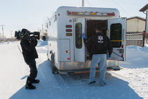 Nurse Dre Erwin in scrubs northern Saskatchewan beside an ambulance, filming a Saskatchewan Union of Nurses commercial.