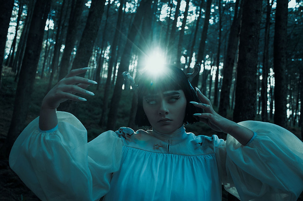 mujer joven de cabello corto en un bosque, con ojos blancos y un vestido blanco, sosteniendo un orbe de luz flotando en sus manos