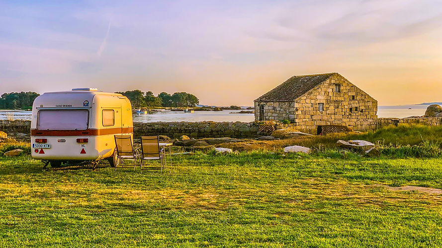 vintage caravan with table and chairs next to the beach