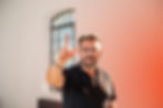 Mann in schwarzem Hemd zeigt mit erhobenem Finger nach vorne – Symbol für Orientierung und Führung.