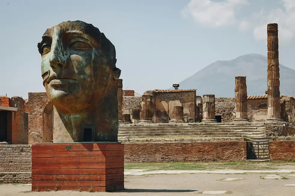 The ruins of Pompeii with a contemporary bronze sculpture and Mount Vesuvius in the background.