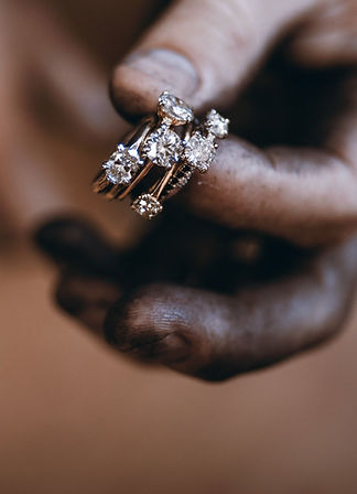 An artisan's metal-stained hand, holding six engagement rings.