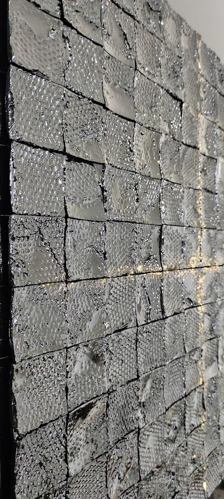 Détail des carrés structurés peints en noir et doré.