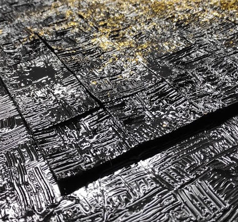 Reflection de la lumière sur les reliefs du support et des carrés noir brillant.