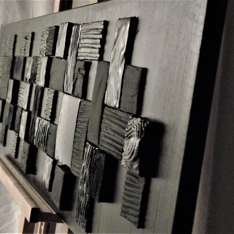 Tableau horizontal abstrait noir composé d'un assemblage de petites toiles enduites et peintes en noirs.