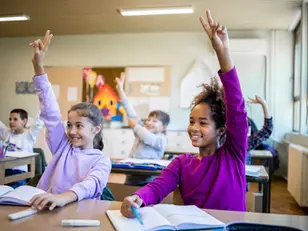 Mindful children raising hands in elementary school classroom during interactive lesson to improve student engagement and social-emotional learning skills with My Mindful Class