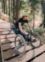 A man with a spinal cord injury is using an adaptive mountain bike to ride on a mountain bike trail in the woods.
