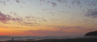Sunset over the Pacific Ocean at Cape Disappointment State Park with North Head Lighthouse visible on the bluff.