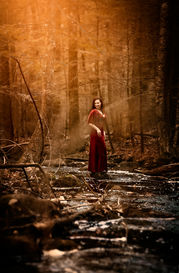 woman smiles on a rock in a stream in New Hampshire forest