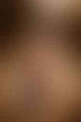 young girl in glasses and orange dress smiles while hugging her little brother in a dry field during family photos in Omaha ne