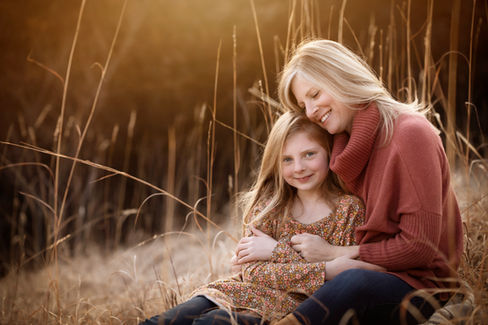 blonde woman holds blonde daughter in tall grass field in Gretna, ne family photo session