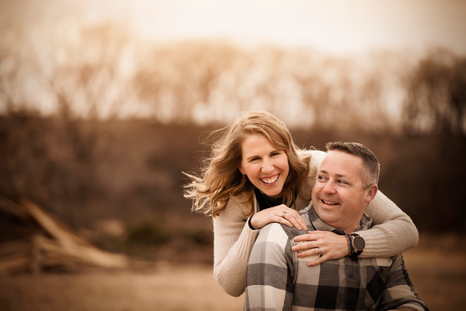Woman laughs and hugs husband during family photo session in Fremont, ne