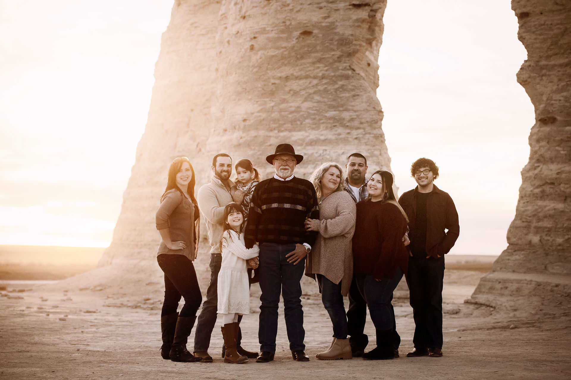 Man in cowboy hat stands with his daughters and their families during family photos at the monument rocks in Kansas