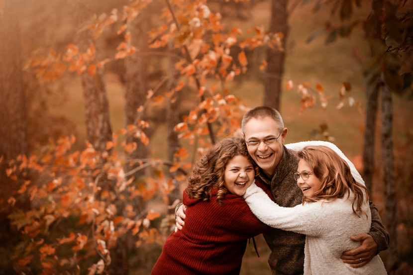 Dad laughs with his daughters in front of orange tree during fall family photos in Ft. Calhoun, NE