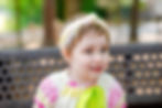 ASK Kourageous Kid Tallulah sitting on a bench under the summer sun.