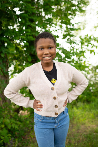 ASK Kourageous Kid Kenya posing in front of lush greenery.