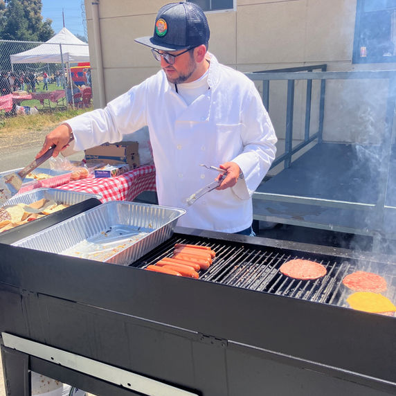 Chef grilling burgers and hot dogs on a large outdoor grill