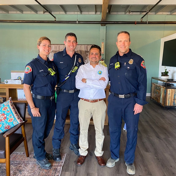 Three firefighters and a man in a white shirt smiling.