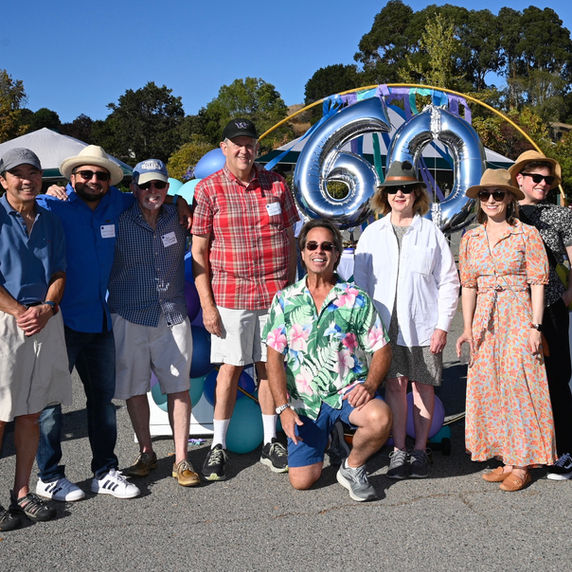 Group of people celebrating a 60th birthday outdoors.