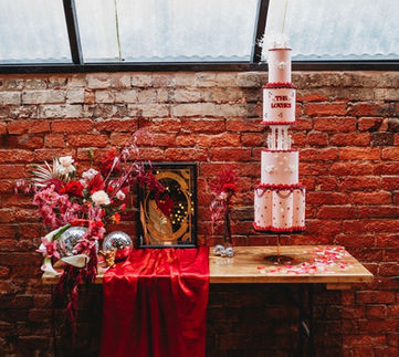 alternative wedding stylist, non traditional wedding styling, alternative wedding inspiration, Vegas wedding inspiration, bold wedding decor, maximalist wedding design, creative wedding styling, editorial wedding shoot, unconventional wedding ideas, rock and roll wedding aesthetic, modern wedding decor, wedding tablescape design, statement wedding backdrop, neon wedding sign, Love You to Death neon, red heart backdrop wedding, sculptural wedding florals, luxury wedding flowers, disco ball wedding decor, checkerboard plinth styling, industrial wedding venue, The Shack Revolution wedding, contemporary wedding design, unique wedding ideas, wedding styling inspiration, dramatic wedding decor, design led wedding concept, wedding reception decor inspiration, alternative wedding collective, modern couple wedding inspiration