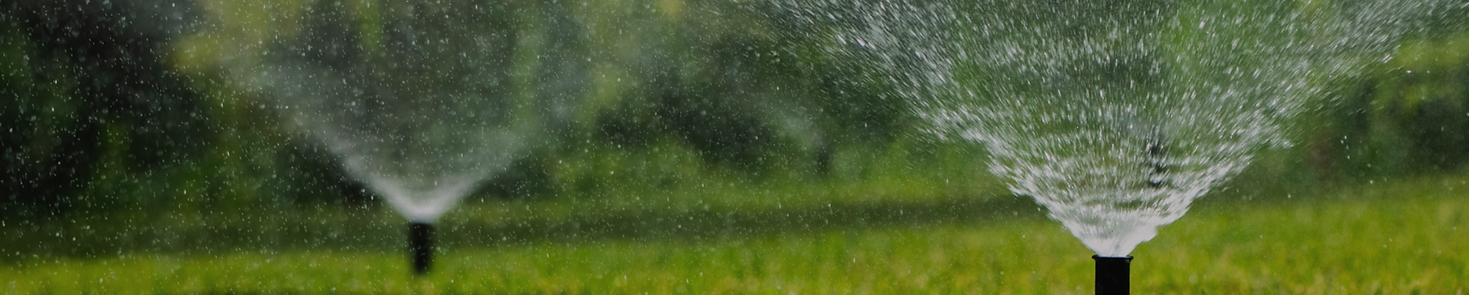Sprinkler system irrigating a green lawn
