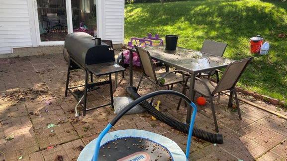 Outdoor dining table covered in dirt and debris, with a grimy floor beneath.