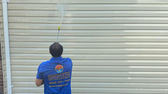 Technician safely power washing house siding for Bright Sunrise Cleaning Solutions.