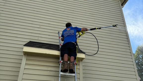 Bright Sunrise Cleaning Solutions technician power washing dirty house siding.