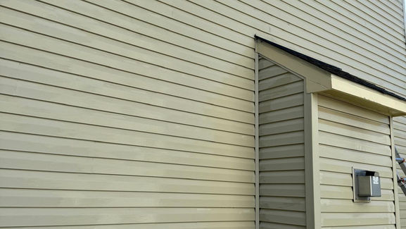 Professional power washing a house, showing exceptional cleaning results.