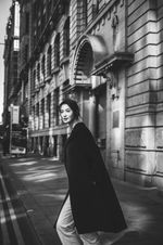 Emi walking on a city sidewalk in black and white