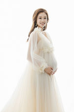Pregnant Letitia in a white gown smiling for Becoming Three