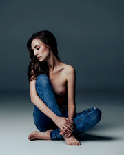 Letitia sitting cross-legged in jeans for Becoming Three.