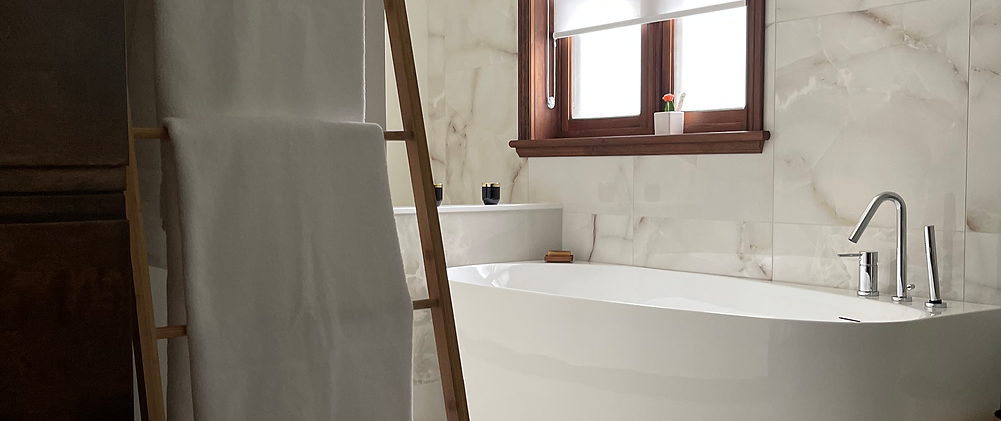 Salle de bain rénovée avec boiseries d’origine et douche en céramique blanche.