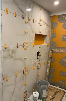 Photo en cours de chantier : mur brut avec membrane orange d’imperméabilisation installée pour la douche.