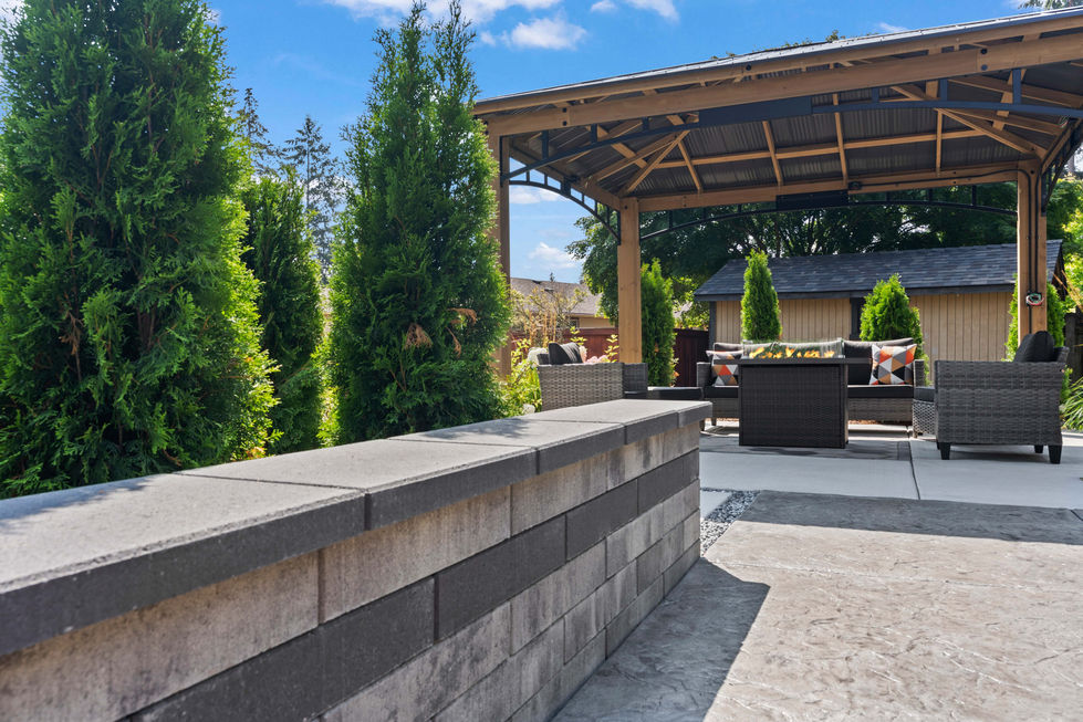 Landscape design and build project in Lakewood, WA, with fireplace, wood pergola, paver patio, and sitting wal