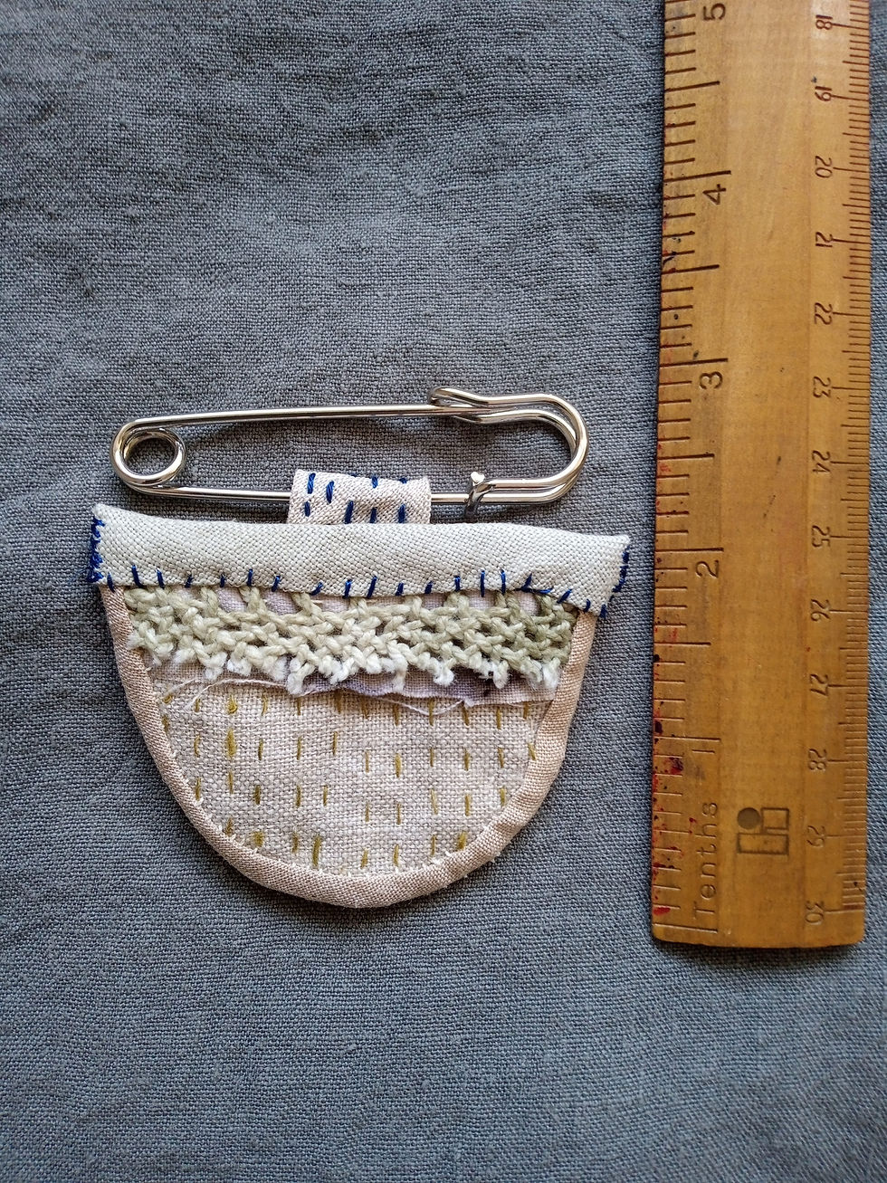 Small hand stitched brooch or protection amulet next to ruler