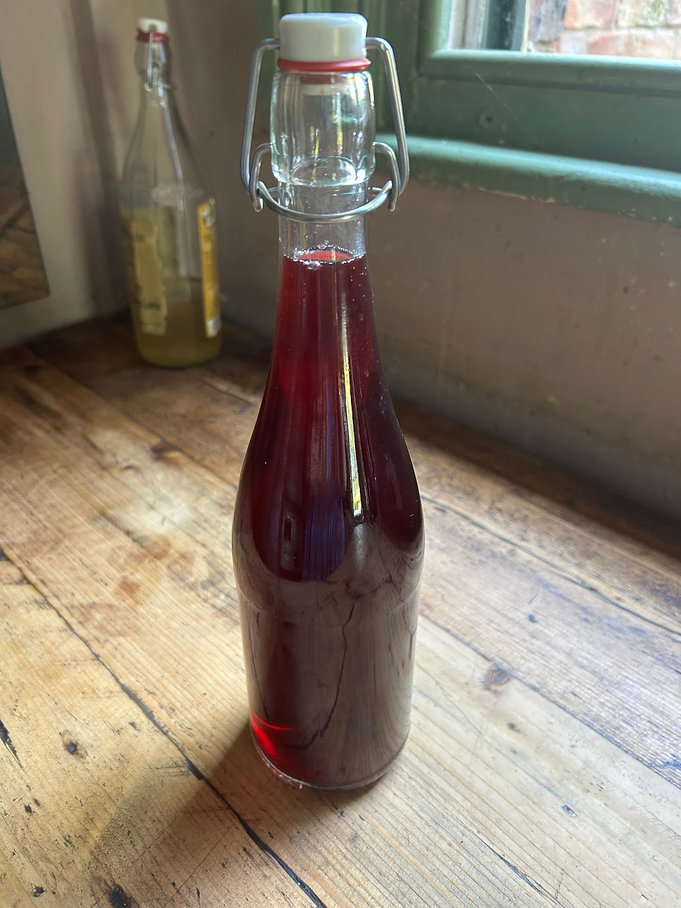 glass bottle of red liquid on wooden surface