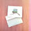 Thumbnail: Greeting card with the state of Alaska and envelope sitting on a pink background