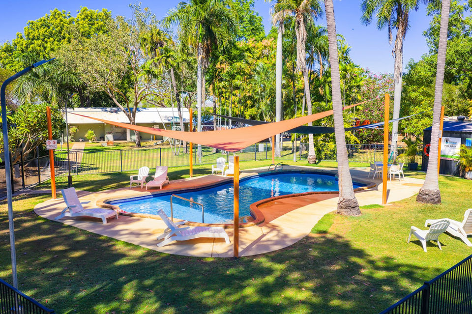 Swimming pool with sunshades and lounge chairs, surrounded by palm trees, Facilities