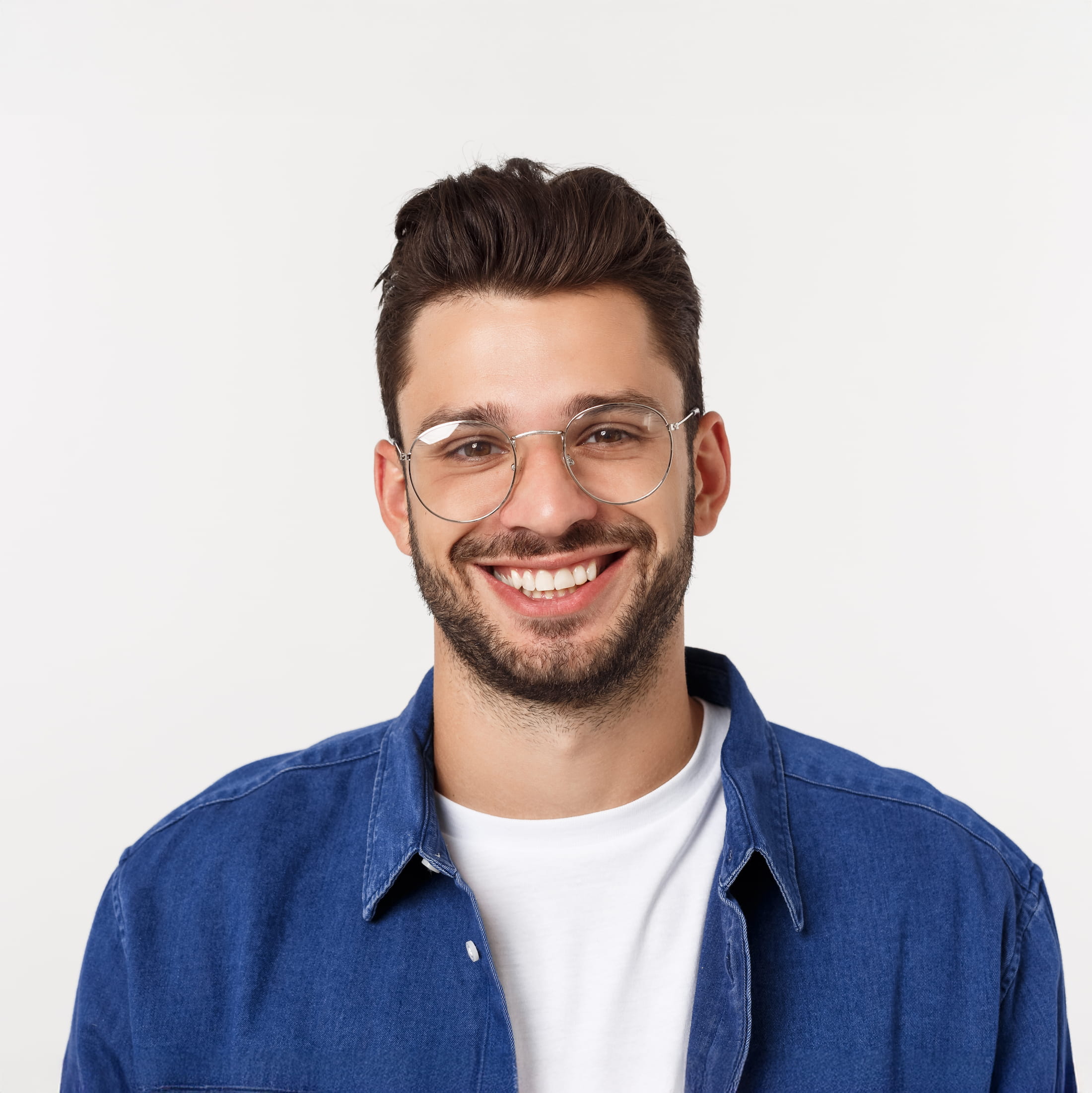 Smiling man wearing glasses, blue shirt, standing in front of white background.