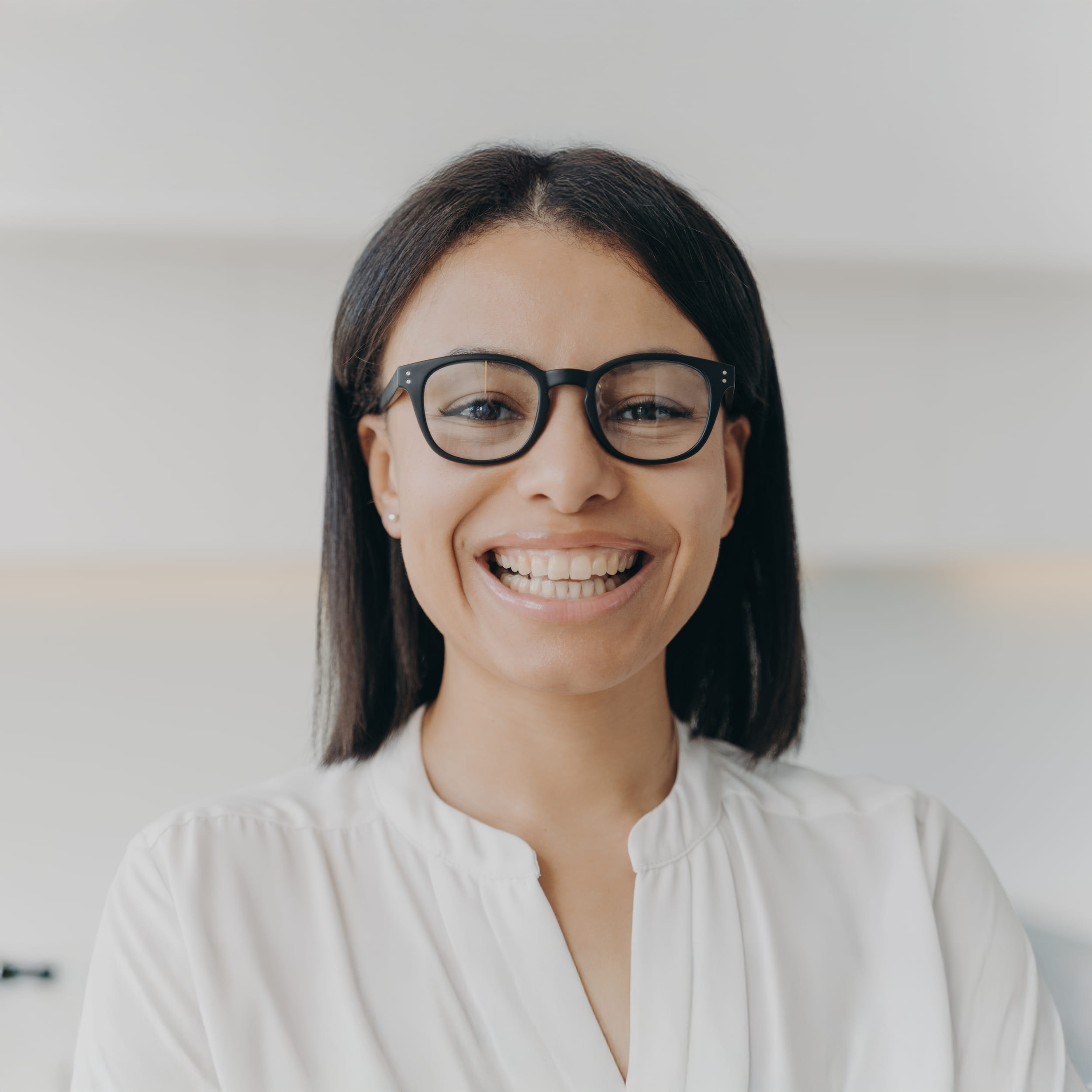 Smiling woman wearing glasses and white shirt, looking directly at the camera.