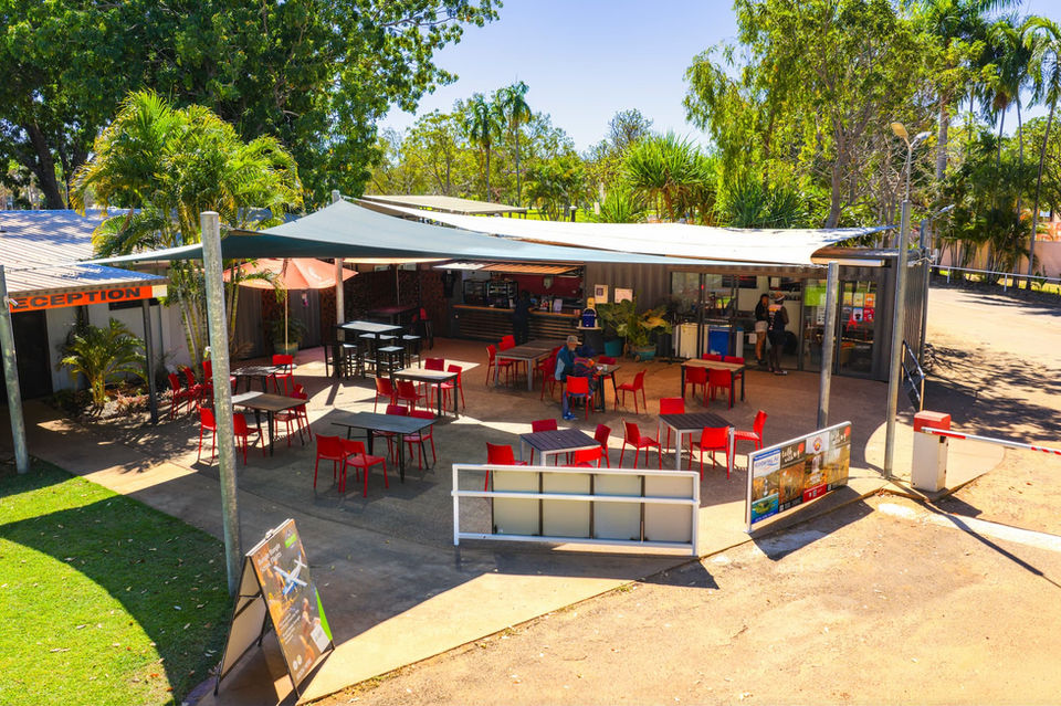 Outdoor restaurant with red tables and visible text, Facilities for dining experience.