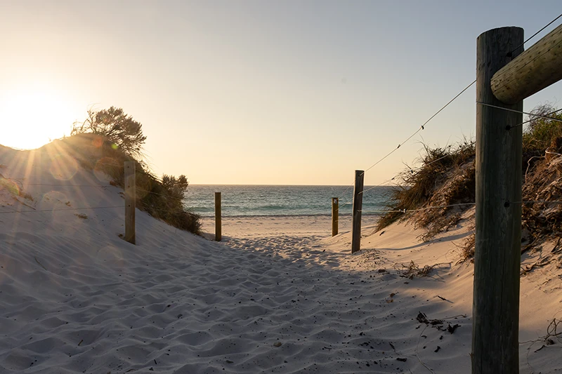a sandy beach with a fence