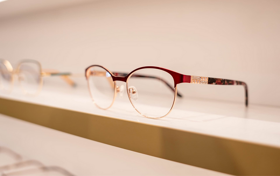 Red and gold eyeglasses, displayed on a shelf. Noranda Optometrist