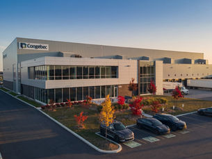 Large two-storey commercial centre at dusk with glazed entries, loading docks and car park