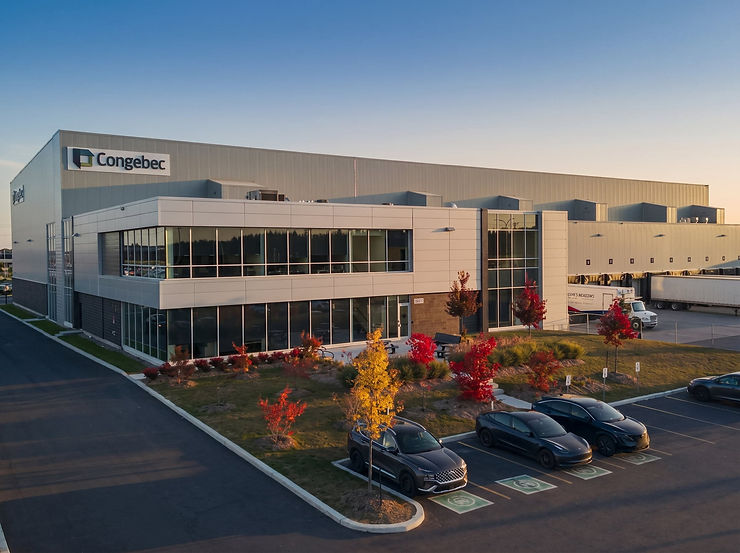 Large two-storey commercial centre at dusk with glazed entries, loading docks and car park