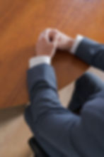Team member in suit with hands clasped on table