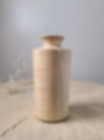 Handcrafted maple bud vase with a cylindrical shape and flared rim styled on a natural wood table top.