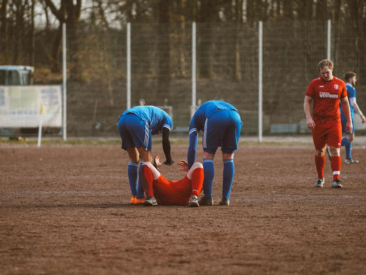 Soccer players assiting an injured player on the opposite team