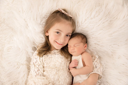 Geschwisterbild eines neugeborenen Mädchen mit Schwester fotografiert in Langenfeld von einem Fotograf für Neugeborenenshooting im Fotostudio photokissesart in der Nähe von Leverkusen, Monheim, Solingen, Leichlingen, Hilden, Haan